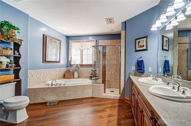 bathroom featuring a garden tub, wood finished floors, a stall shower, and a sink