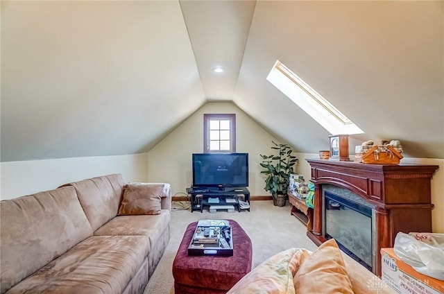 living area with a glass covered fireplace, vaulted ceiling with skylight, baseboards, and carpet