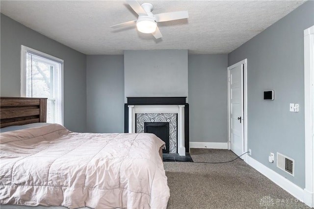 unfurnished bedroom featuring baseboards, visible vents, carpet floors, a tile fireplace, and a textured ceiling