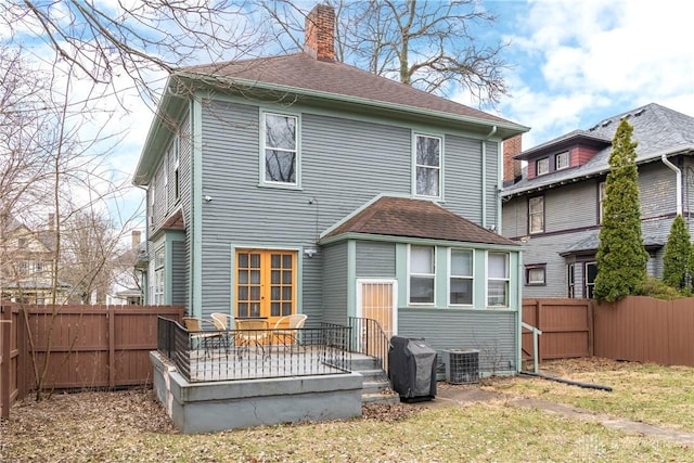 rear view of property featuring central air condition unit, a chimney, a fenced backyard, and roof with shingles