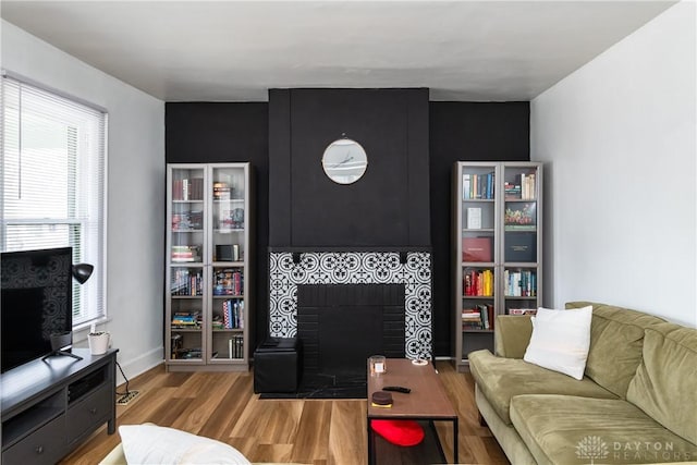 living room featuring baseboards, wood finished floors, and a fireplace