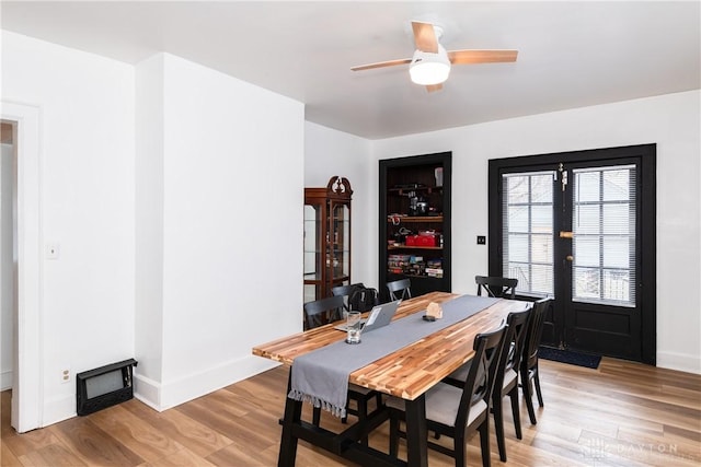 dining space with a ceiling fan, light wood-type flooring, and baseboards