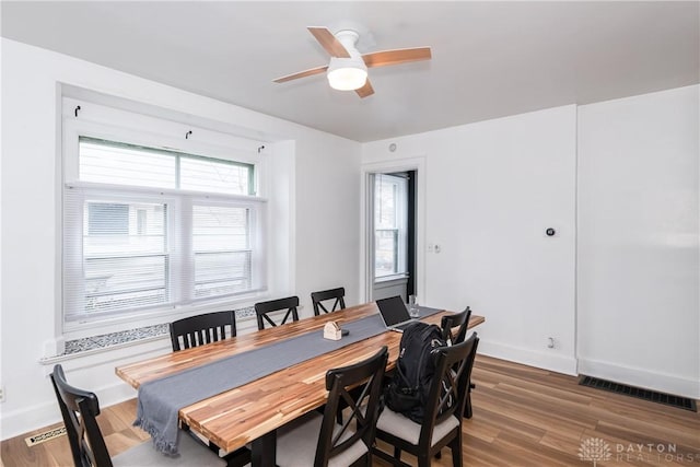 dining area with visible vents, a ceiling fan, baseboards, and wood finished floors