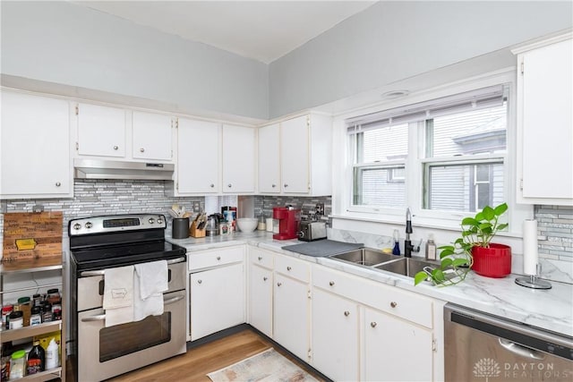 kitchen featuring backsplash, under cabinet range hood, white cabinets, stainless steel appliances, and a sink