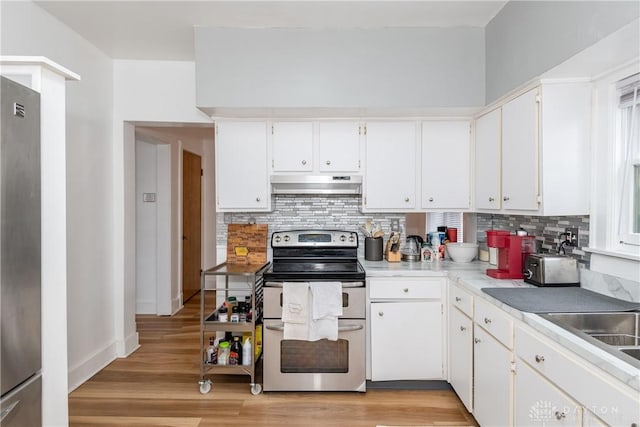 kitchen with under cabinet range hood, decorative backsplash, light wood-style flooring, and appliances with stainless steel finishes