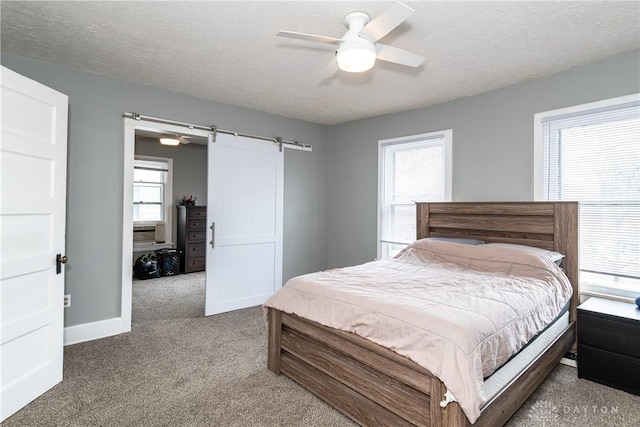 carpeted bedroom featuring a barn door, multiple windows, and a textured ceiling