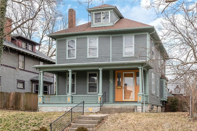 traditional style home with a porch, a chimney, roof with shingles, and fence