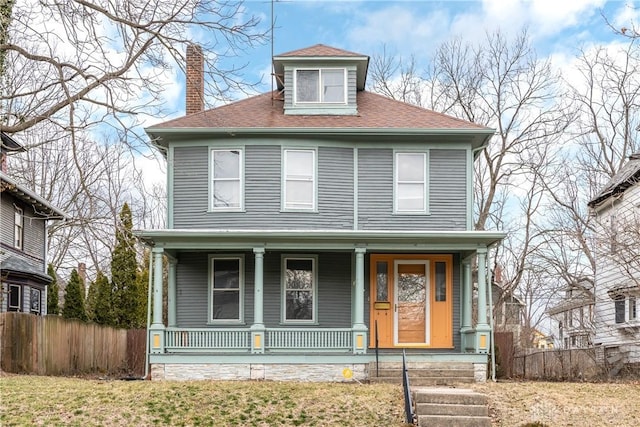 traditional style home featuring a front lawn, fence, covered porch, a shingled roof, and a chimney