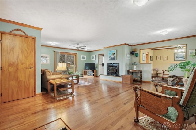 living room with ornamental molding, wood finished floors, and ceiling fan