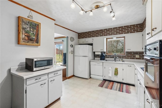 kitchen with light floors, light countertops, white cabinets, white appliances, and a sink