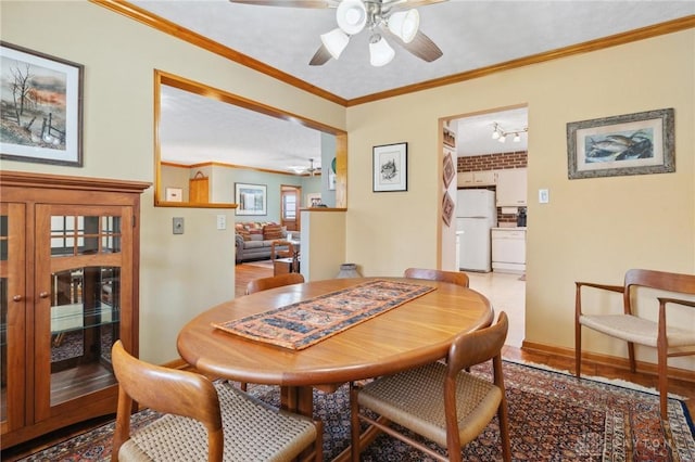 dining area with baseboards, wood finished floors, ceiling fan, and crown molding