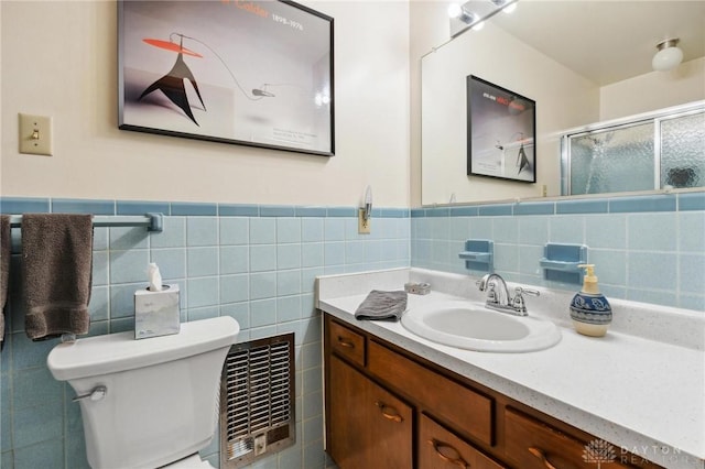 bathroom featuring visible vents, a shower stall, toilet, vanity, and tile walls