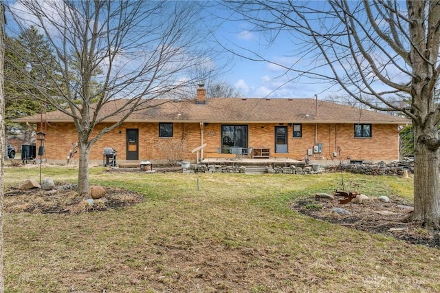 rear view of house with a yard, brick siding, and a chimney