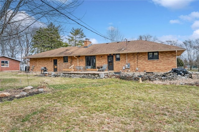 rear view of property with a patio, a yard, roof with shingles, brick siding, and a chimney