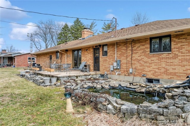 rear view of house featuring brick siding, a patio area, a chimney, and a lawn