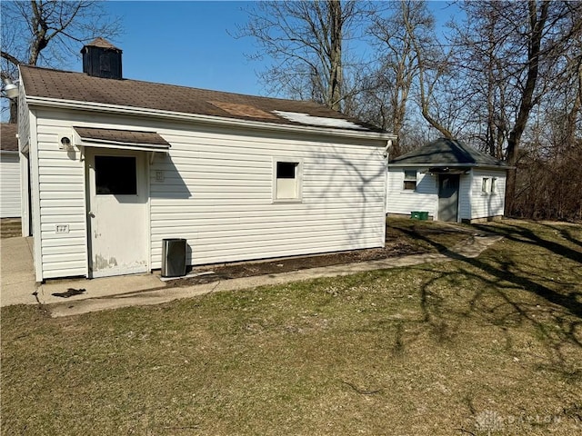 back of house with an outbuilding, a lawn, and a chimney