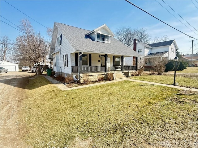 view of front facade with an outbuilding, dirt driveway, covered porch, roof with shingles, and a front yard