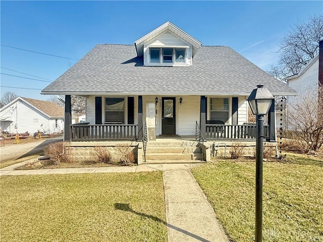 bungalow-style house featuring a porch, a shingled roof, and a front lawn