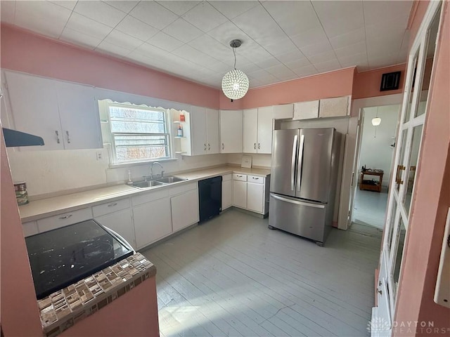 kitchen featuring a sink, decorative light fixtures, freestanding refrigerator, white cabinets, and dishwasher