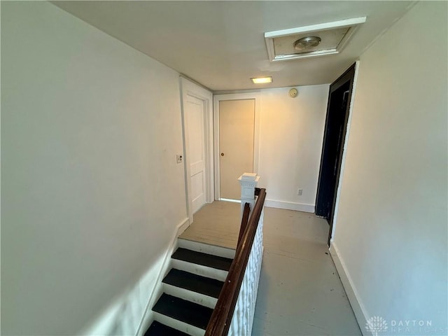 stairs with baseboards, attic access, and finished concrete floors