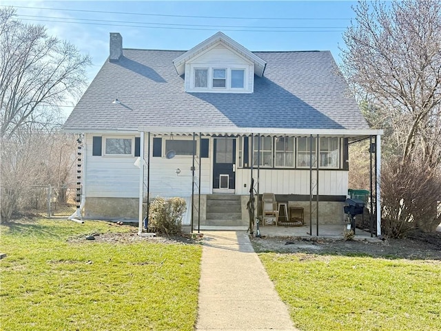 view of front of house featuring fence, roof with shingles, a sunroom, entry steps, and a front lawn