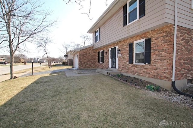 view of side of property featuring brick siding and a lawn