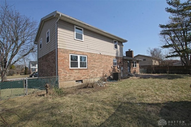 back of property with brick siding, central air condition unit, a yard, and fence