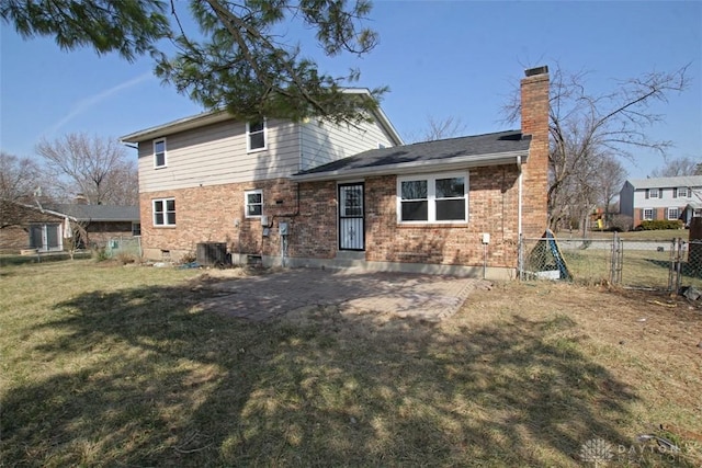 back of house with brick siding, fence, central air condition unit, a chimney, and a yard