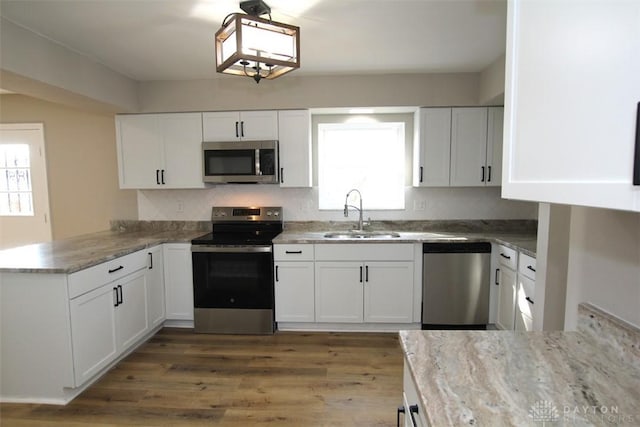 kitchen with a sink, a peninsula, white cabinets, and stainless steel appliances