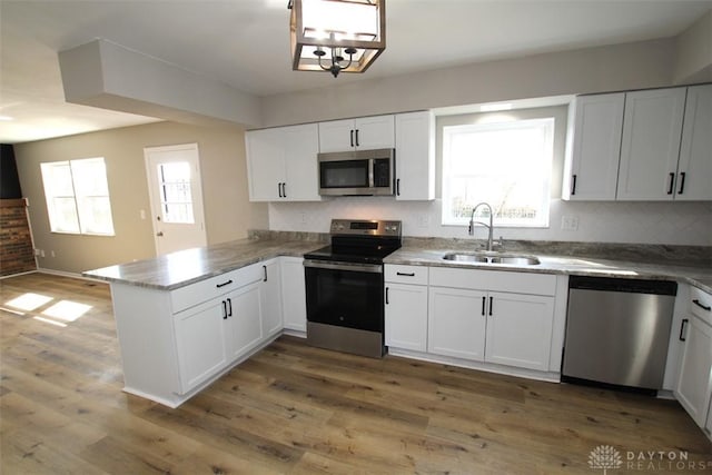 kitchen featuring a wealth of natural light, a peninsula, stainless steel appliances, and a sink