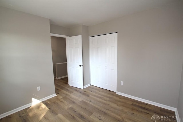 unfurnished bedroom featuring a closet, baseboards, and wood finished floors