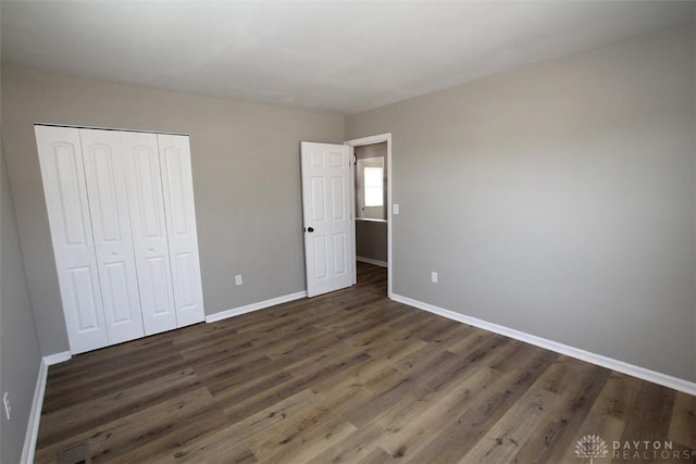 unfurnished bedroom with a closet, baseboards, and wood finished floors