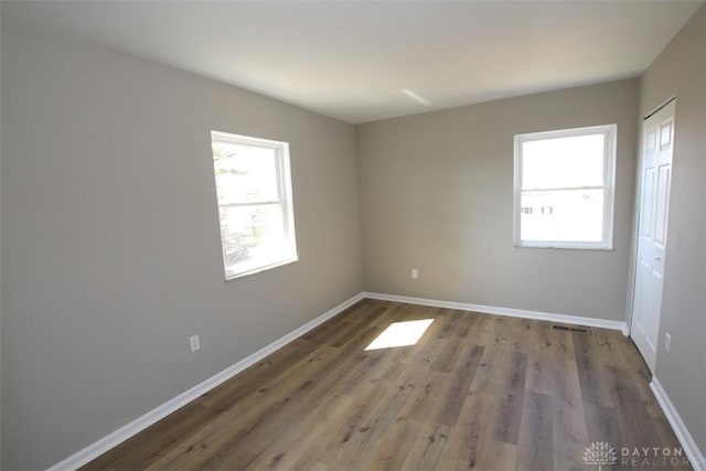 unfurnished room with wood finished floors, a healthy amount of sunlight, and baseboards