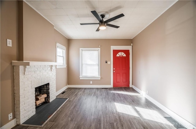 foyer entrance with visible vents, wood finished floors, baseboards, a brick fireplace, and ceiling fan