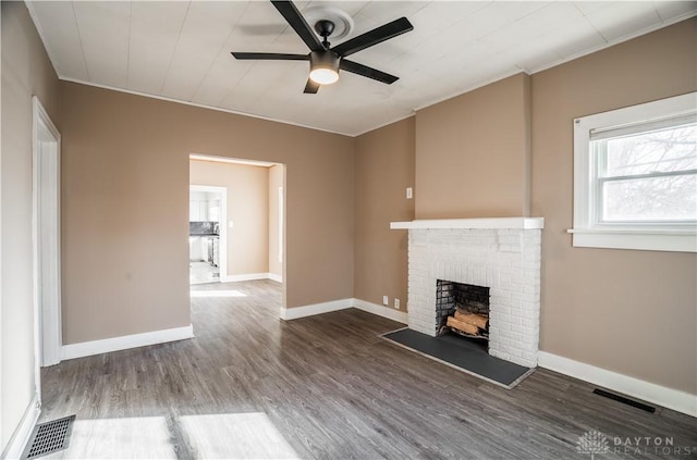 unfurnished living room with a ceiling fan, wood finished floors, visible vents, baseboards, and a brick fireplace