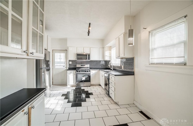 kitchen with a sink, dark countertops, backsplash, and stainless steel appliances