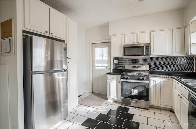 kitchen with stainless steel appliances, dark countertops, white cabinets, and decorative backsplash