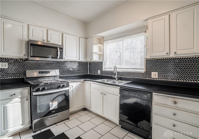 kitchen with a sink, dark countertops, white cabinetry, and stainless steel appliances