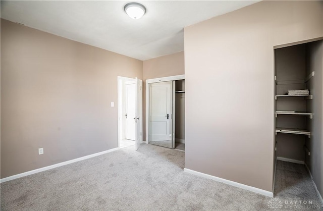 unfurnished bedroom with a closet, carpet flooring, and baseboards