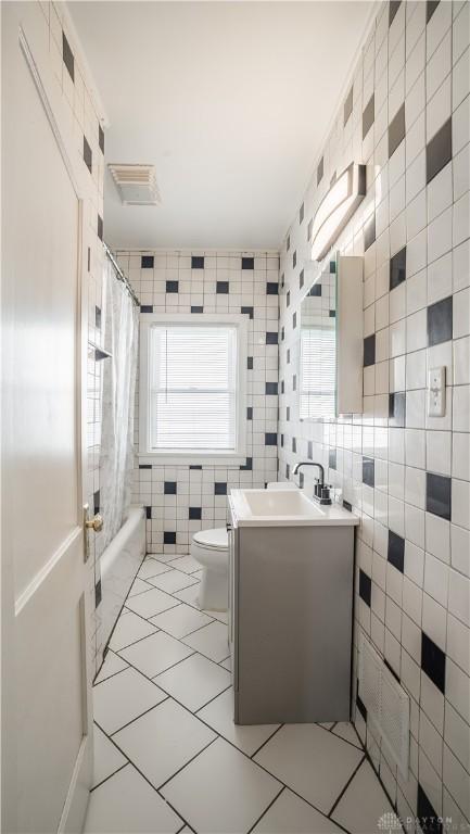 full bath with toilet, tile walls, vanity, and shower / bath combination with curtain