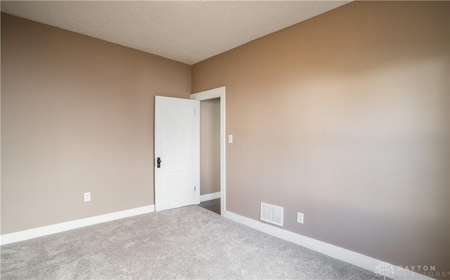 unfurnished room with baseboards, carpet floors, a textured ceiling, and visible vents