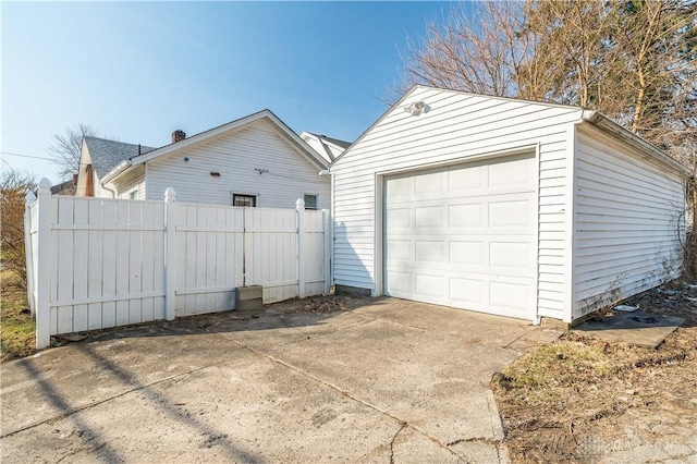 detached garage with concrete driveway and fence