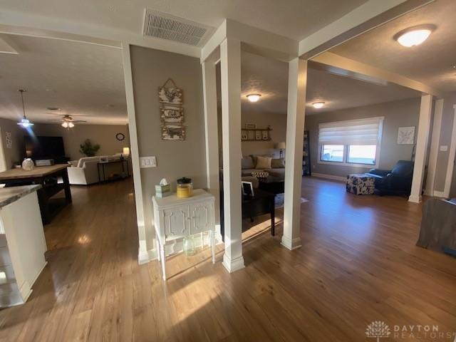 hall featuring wood finished floors, visible vents, and baseboards