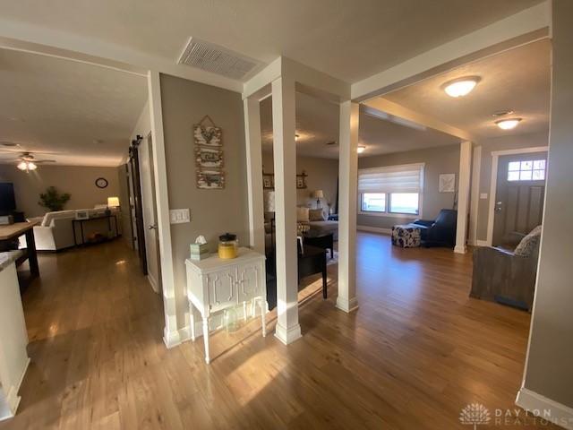 corridor with a barn door, baseboards, visible vents, and wood finished floors