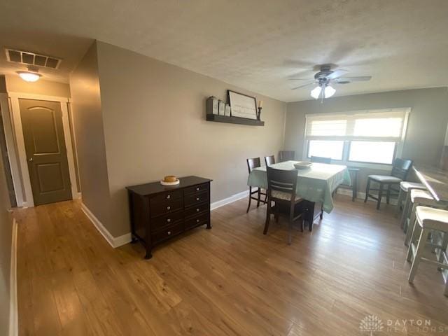 dining room with visible vents, baseboards, wood finished floors, and a ceiling fan