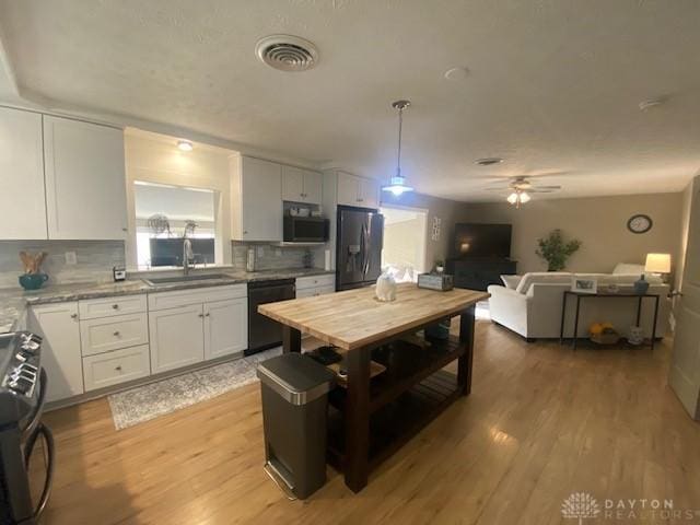 kitchen with fridge with ice dispenser, visible vents, a sink, white cabinets, and dishwasher