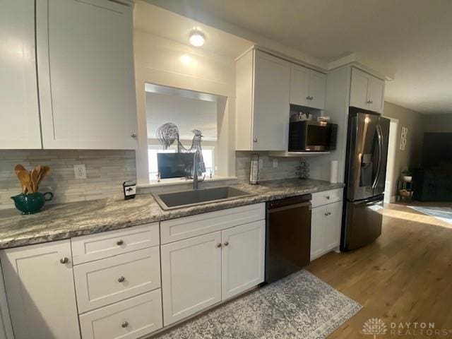 kitchen with a sink, decorative backsplash, white cabinetry, and stainless steel appliances