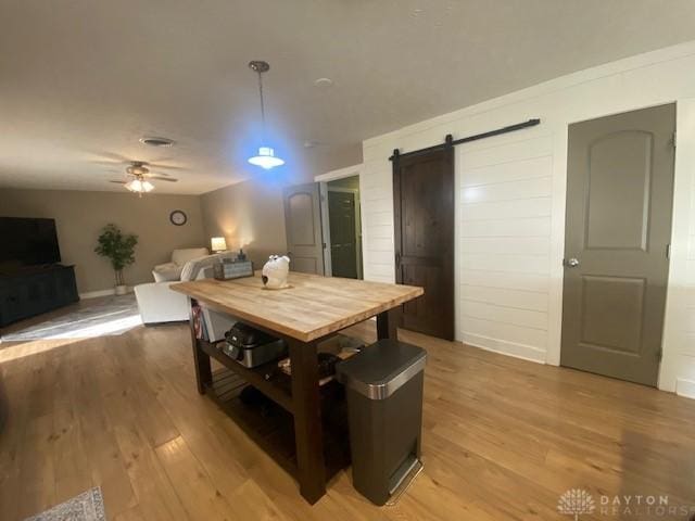 dining room with ceiling fan, light wood-style floors, and a barn door