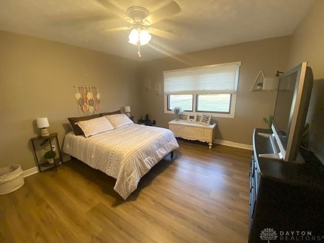 bedroom with wood finished floors, baseboards, and ceiling fan