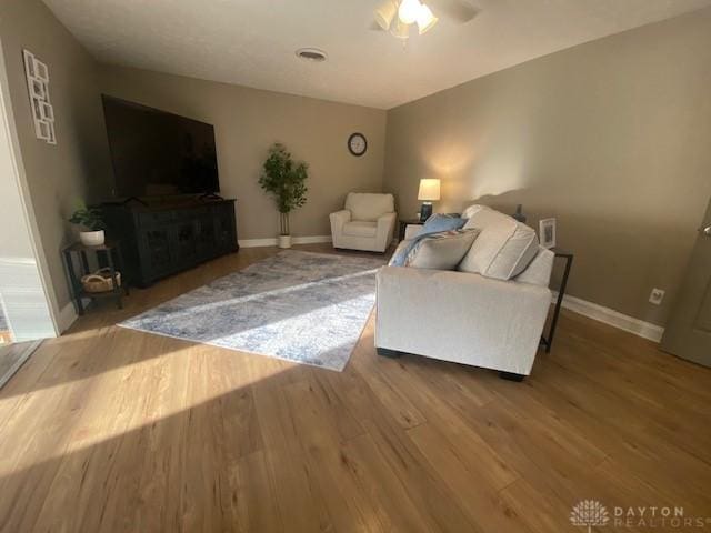 living area featuring a ceiling fan, baseboards, and wood finished floors